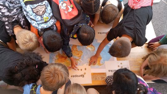 Kinder betzrachten eine Weltkarte