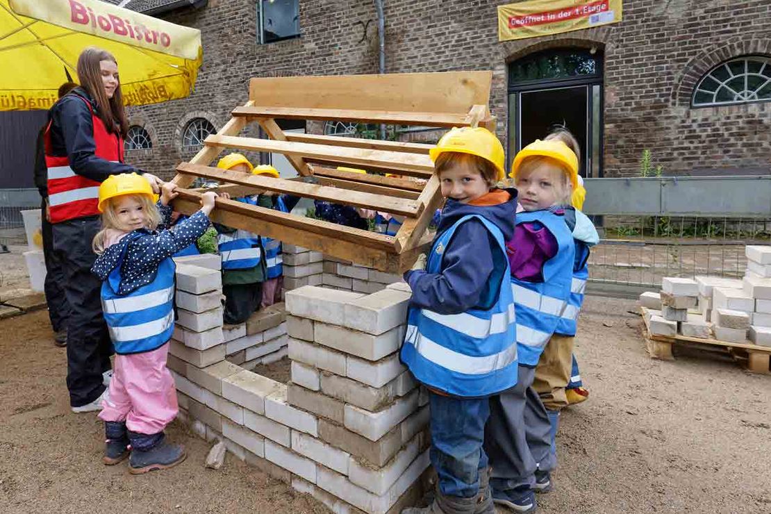Kinder bauen ein Haus aus Steinen