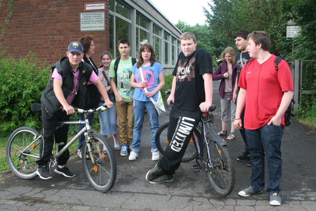 Schüler:innen stehen mit Fahrrädern vor dem Schulgelände
