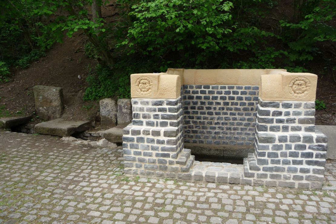 Das Bild zeigt eine aus Stein erbaute Rekonstruktion der römischen Brunnenstube "Grüner Pütz".