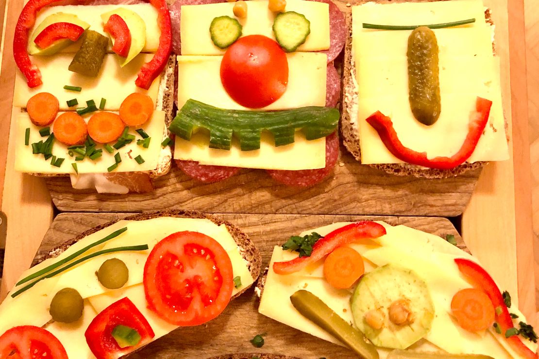 Gesichter aus Obst und Gemüse auf Brotscheiben
