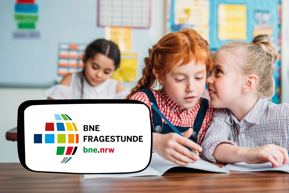 Zwei Mädchen flüstern im Klassenraum.