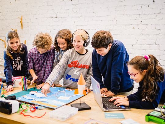 Sechs Kinder nutzen digitale Werkzeuge und gestalten gemeinsam ein interaktives Plakat.