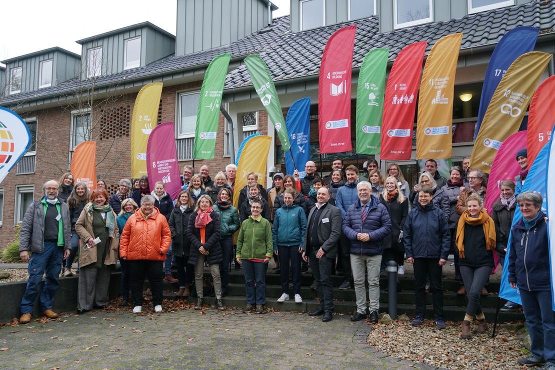 Eine Gruppe von Menschen vor einem Tagungshaus. Im Hintergrund sind Fahnen mit den SDGs.