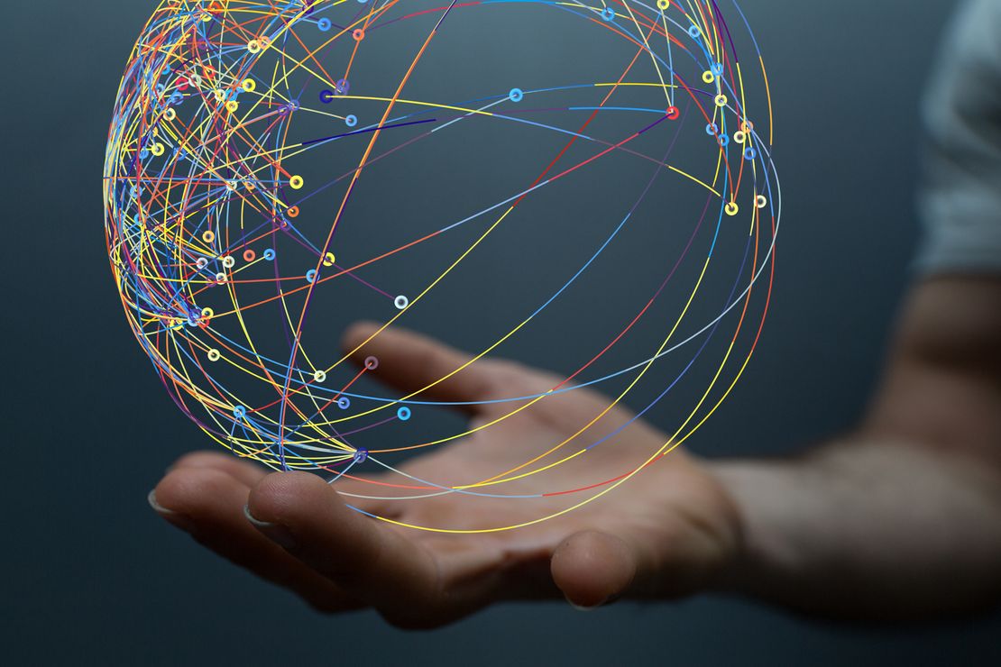 Eine Hand hält eine virtuelle Kugel, auf der durch Linien und Kreise in verschiedenen Farben ein Netzwerk dargestellt ist.