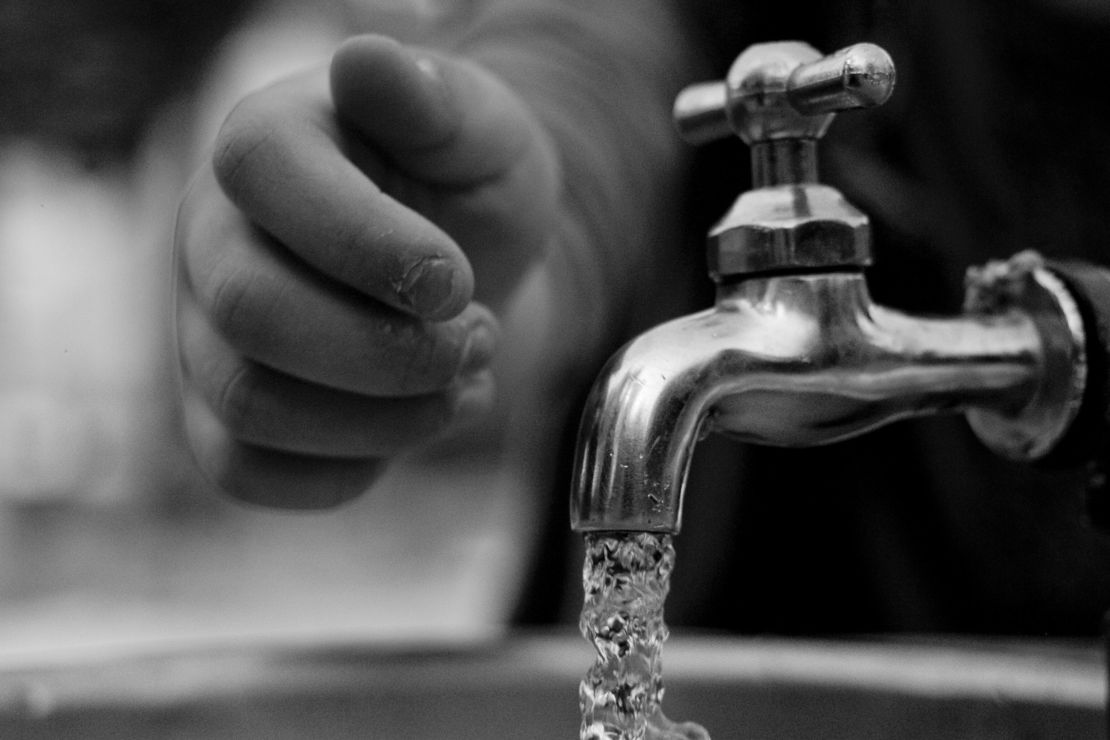 Eine Person hat gerade einen Wasserhahn aufgedreht und es läuft Wasser aus dem Hahn.