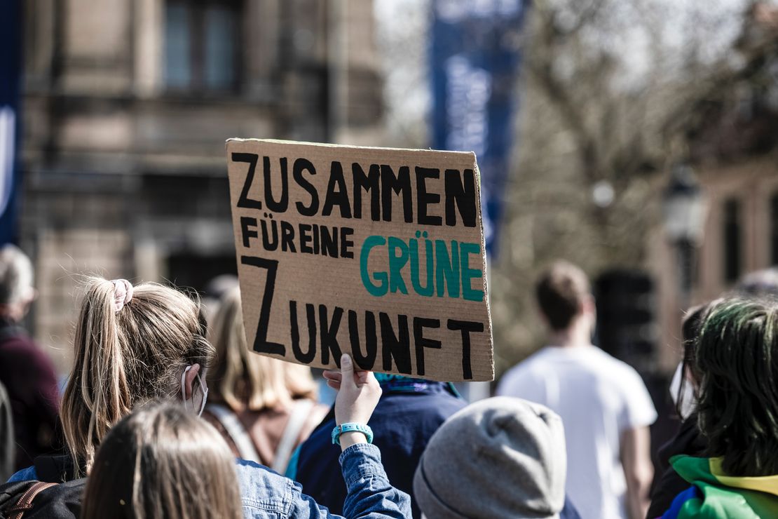 Person hält auf Demonstration Schild mit Aufschrift: Zusammen für eine grüne Zukunft