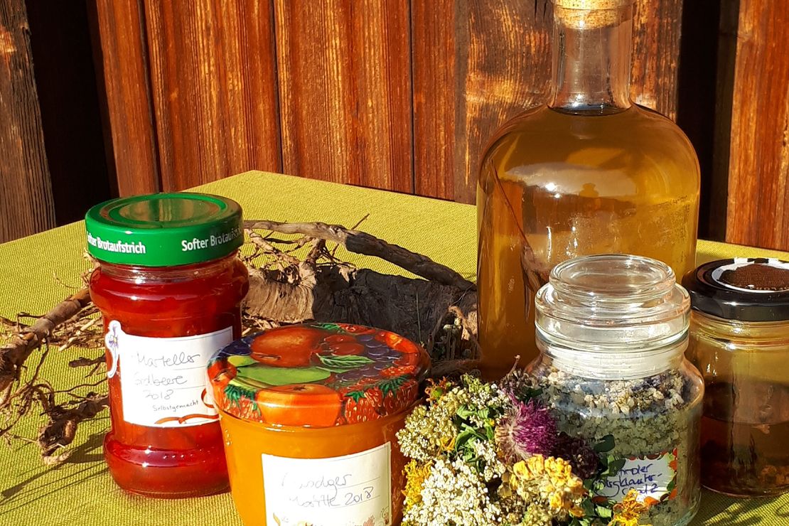 Tisch mit Kräutersalz, Marmeladengläsern, Sirupflasche und Kräuterstrauß