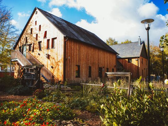 Hier sieht man das Haus der Natur, ein altes Bauernhaus, dass von Außen mit Holz verschalt wurde. Vor dem Haus der Natur befindet sich ein liebevoll angelegter Bauerngarten.