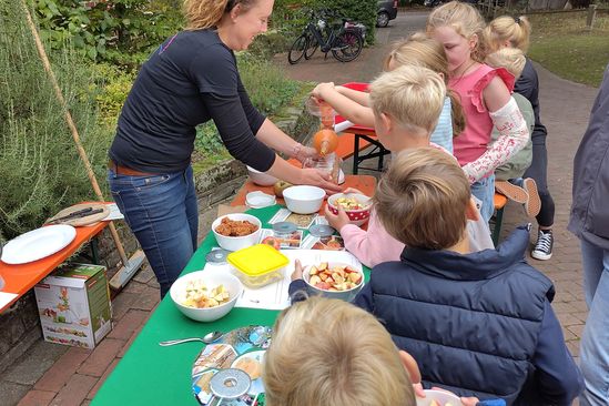 Kinder pressen selber Apfelsaft mithilfe einer Handpresse