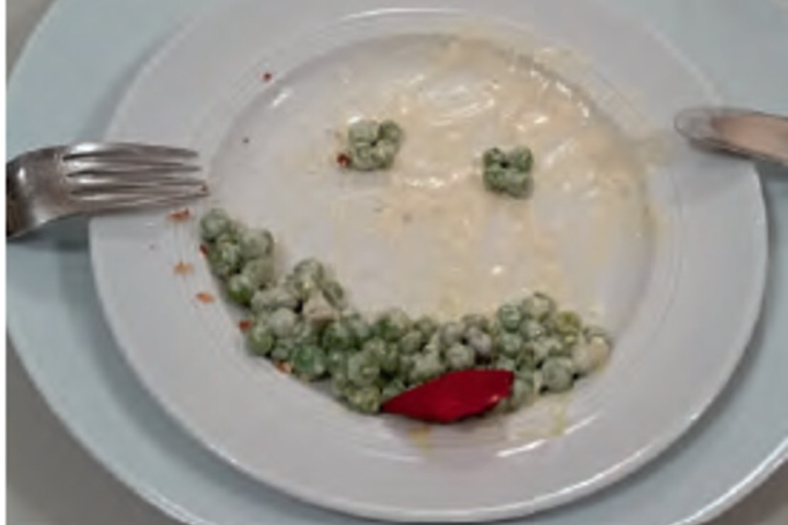 Ein Teller, auf dem aus Erbsen ein Smileygesicht gelegt wurde