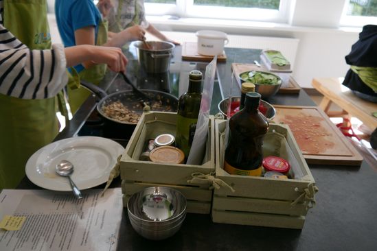 Leckere Zutaten für ein Gericht sind neben einer Pfanne  angerichtet. Schüler*innen bereiten diese zu.