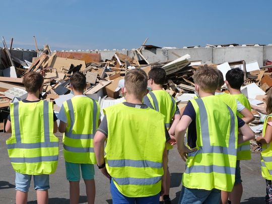 Eine Schulklasse besichtigt den Wertstoffhof der EGW und schaut auf einen Berg von Altholz-Abfällen.