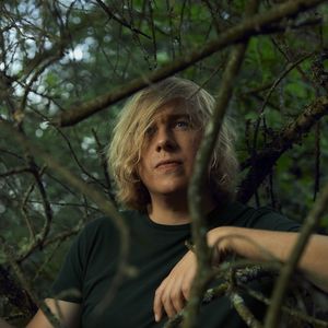 Dominik Eulberg umgeben von grünen Blättern und Ästen