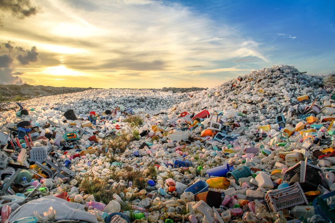 Ein Berg aus Plastikmüll bis zum Horizont mit blauen Himmel und aufziehenden Wolken.