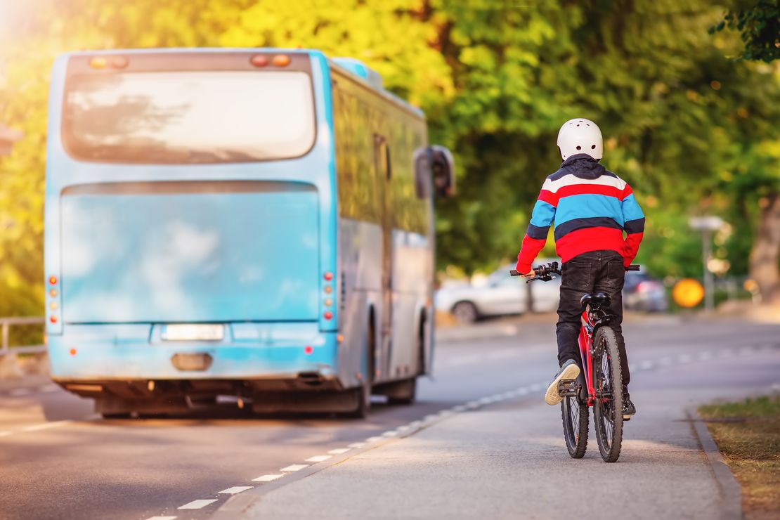 Boy on a bicycle trying to catch up with a blue bus.